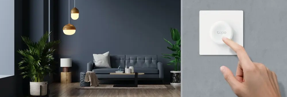 Chytrý stmívač Tp-Link Tapo S200D na stěně obývacího pokoje a ruka, která ho mačká